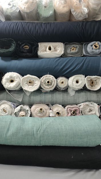 Các cuộn vải polyester và vải pha chồng lên nhau tại cửa hàng dệt may — tiêu chí chọn vải polyester sỉ