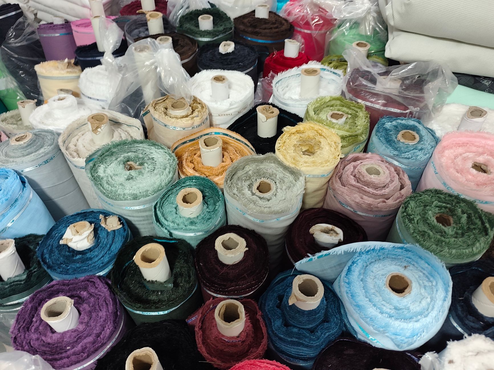 Vibrant mix of fabric rolls in various colors at a textile store, offering a broad selection.