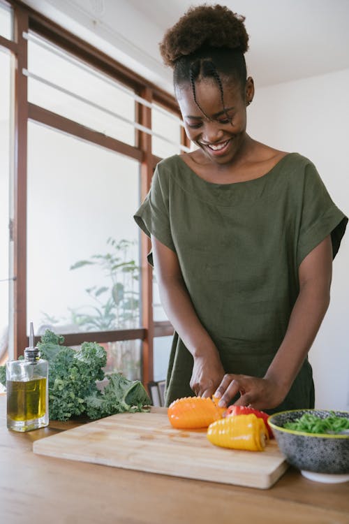 Free Woman in Green Tank Top Holding Orange Bell Pepper Stock Photo