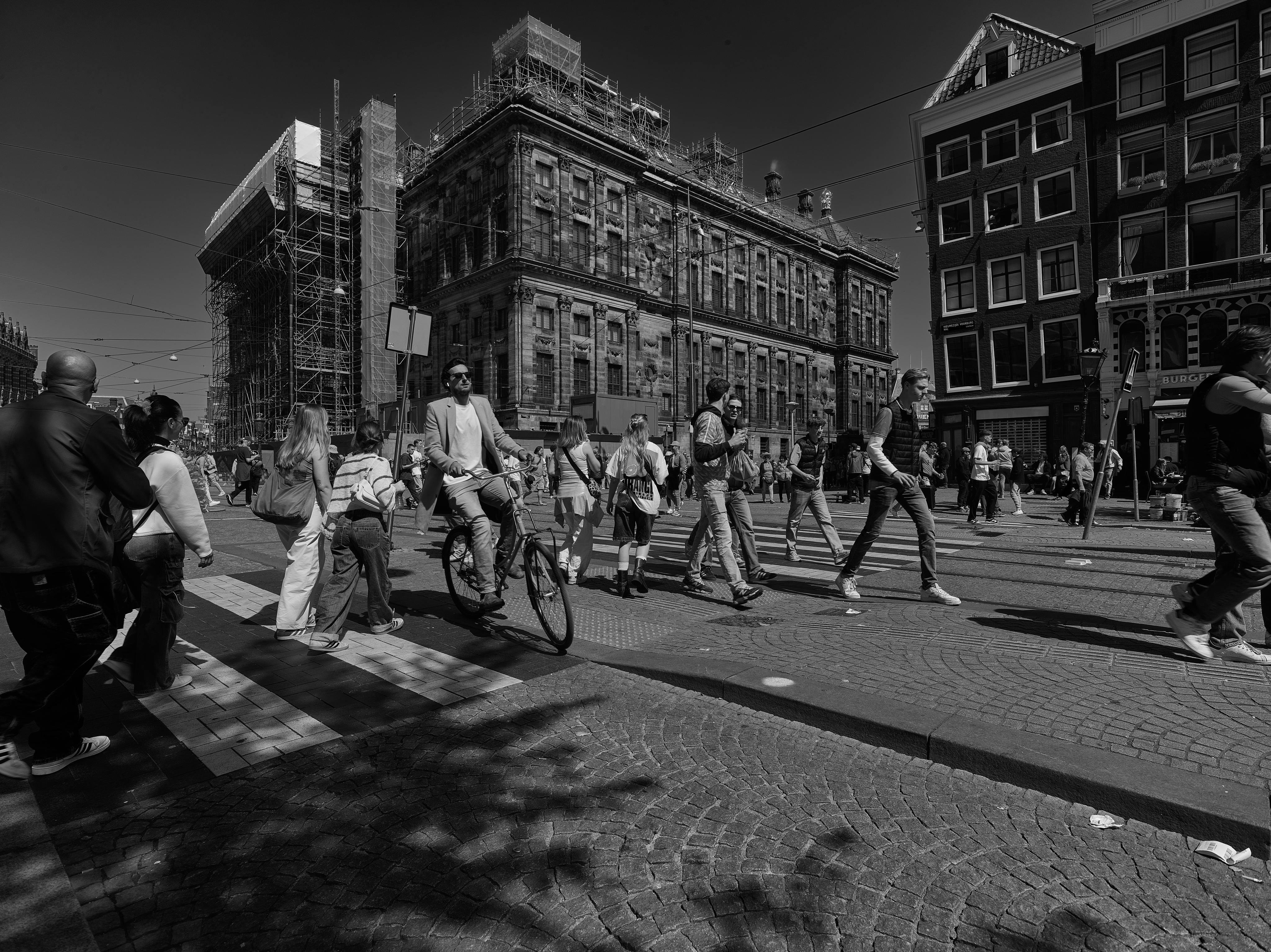 Bezpłatne Czarno-biały obraz dynamicznej ulicy miejskiej pełnej pieszych i rowerzystów. Zdjęcie z galerii