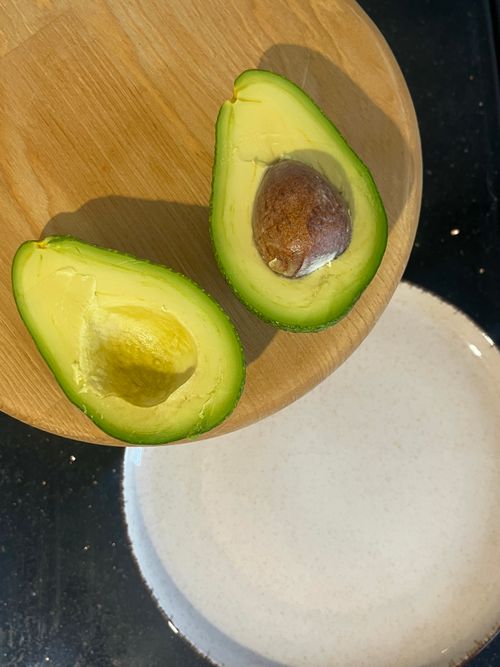 Free Two fresh avocado halves on a wooden board displaying vibrant green flesh and pit. Stock Photo