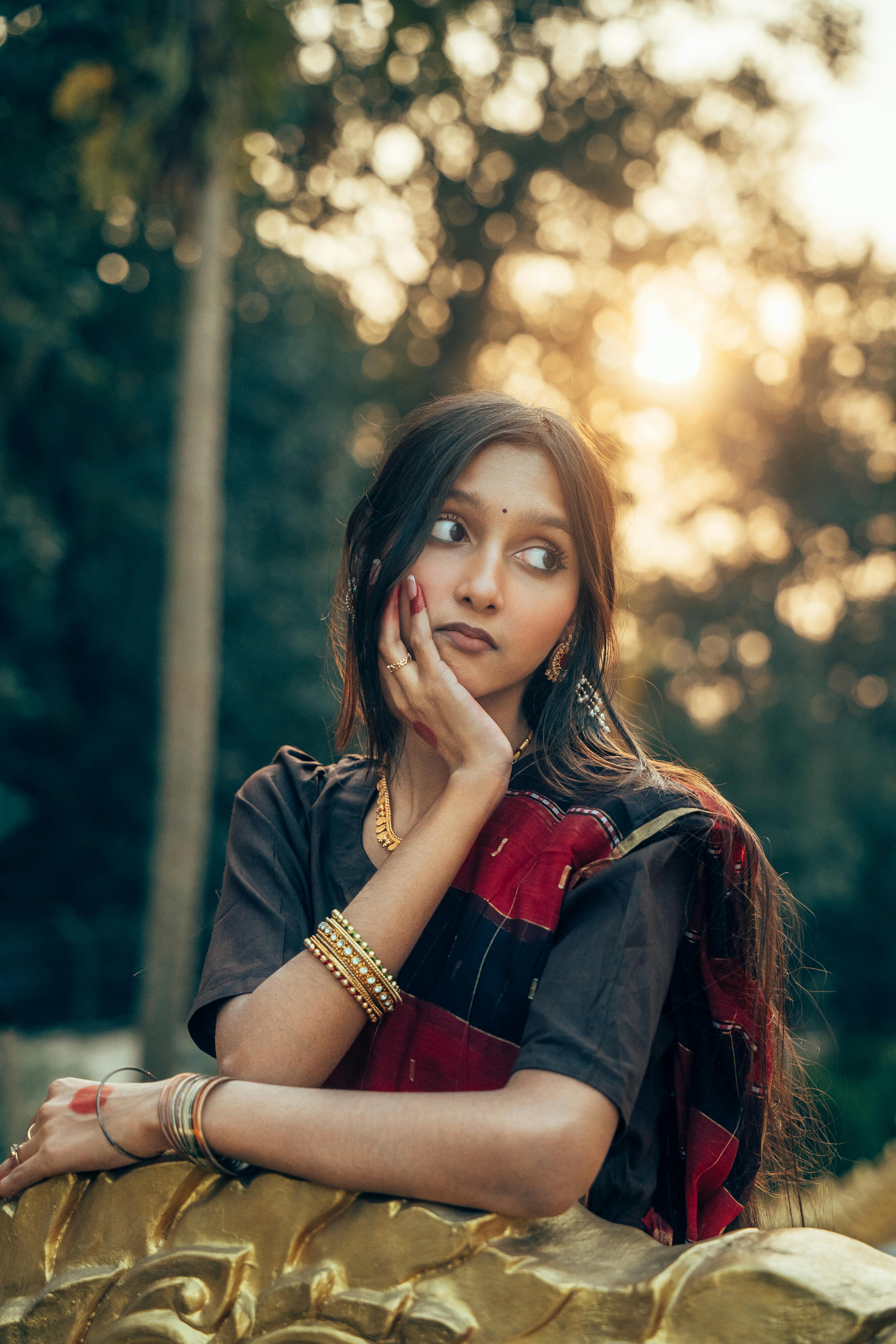 Ücretsiz Güney Asyalı genç bir kız, geleneksel kıyafetleriyle gün batımında açık havada düşünceli bir şekilde poz veriyor. Stok Fotoğraflar