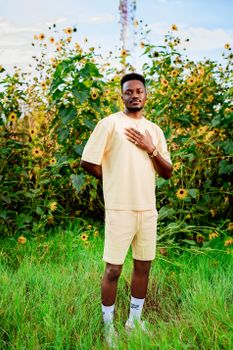 Portrait of a stylish young man standing in a sunflower field in Windhoek, Namibia, under natural light.