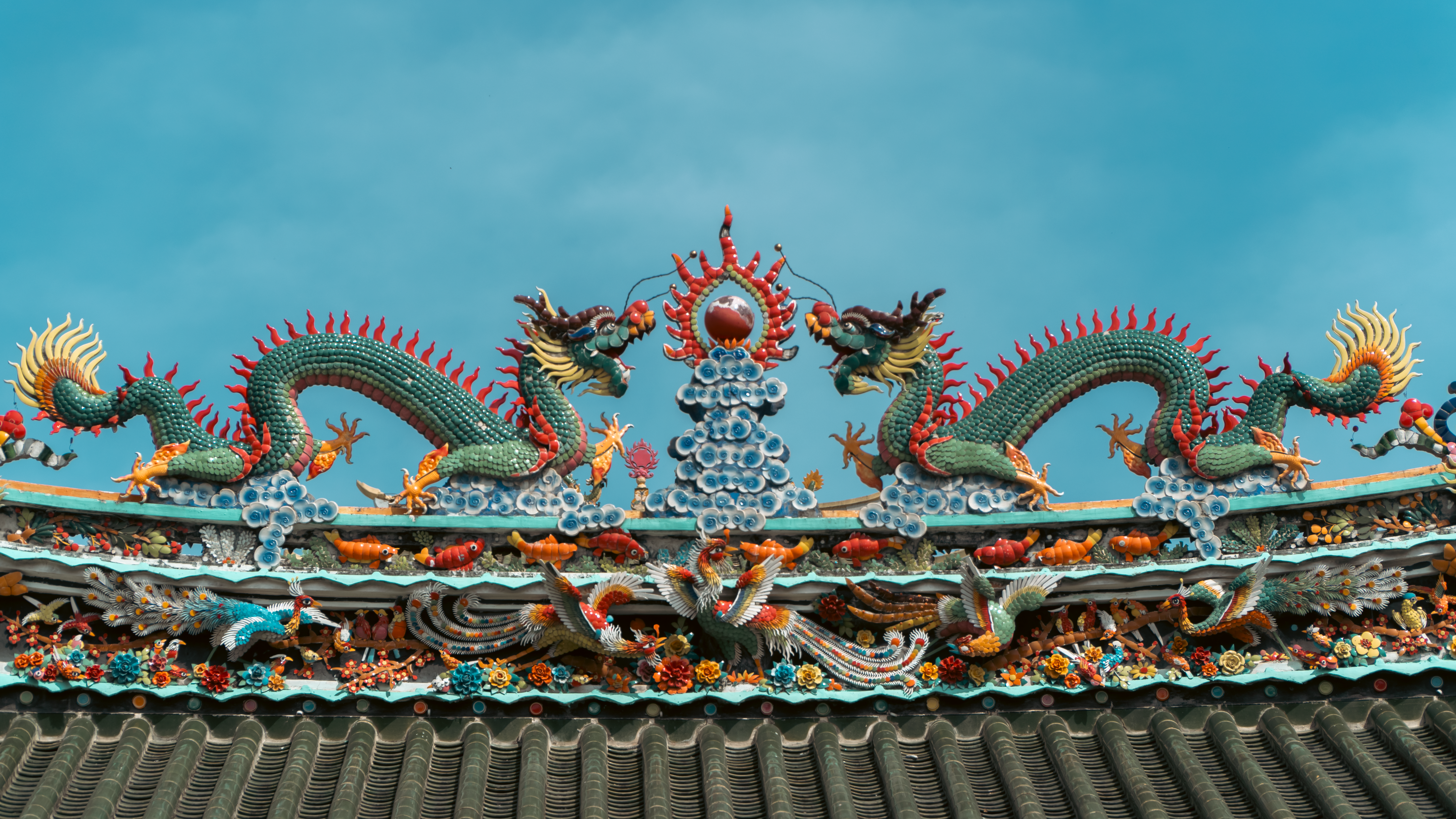 Intricate dragon sculptures on a temple roof under a clear sky.