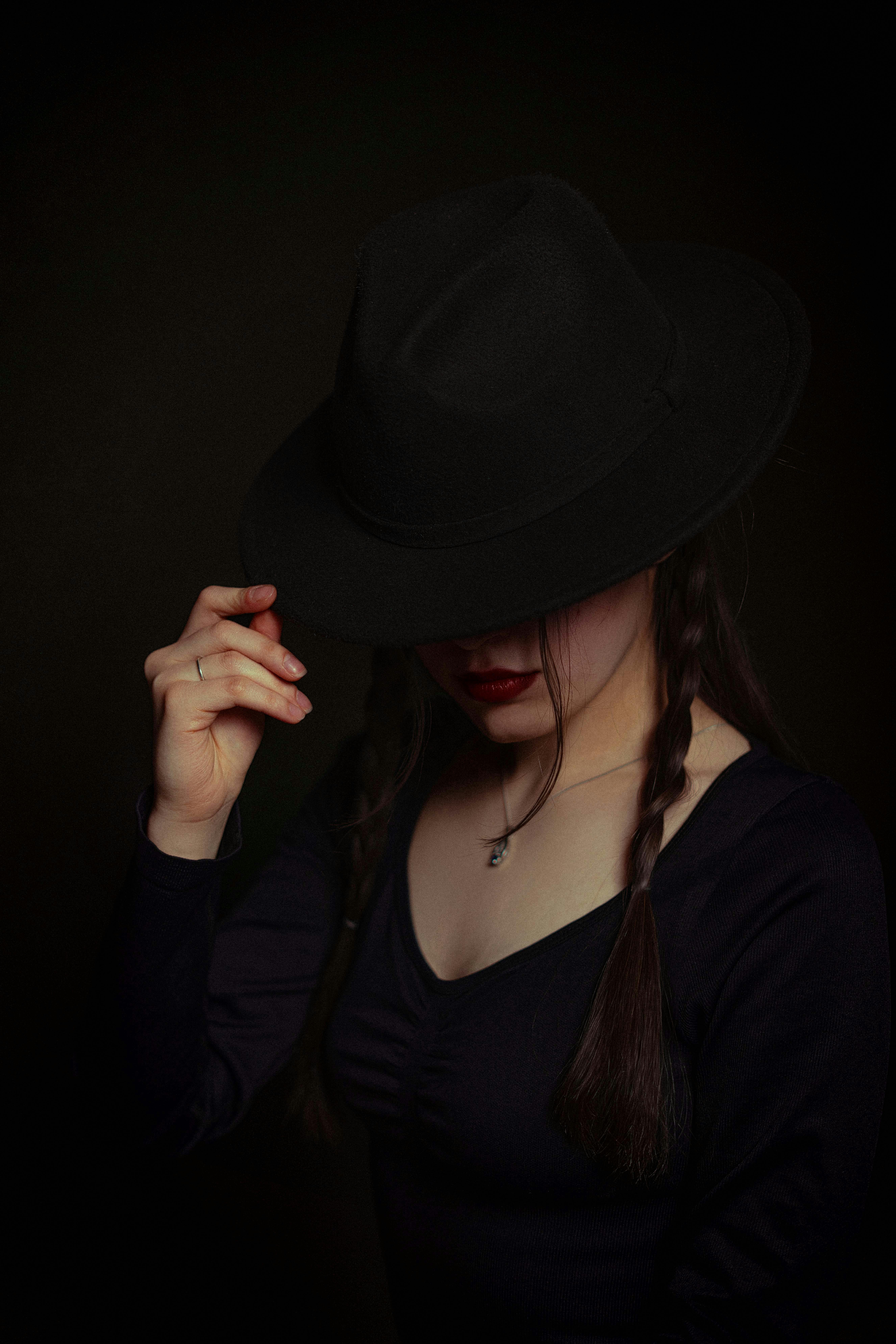 Gratis En mystisk kvinde i et mørkt outfit og hat, der udstråler elegance og gådefuldhed. Lagerfoto