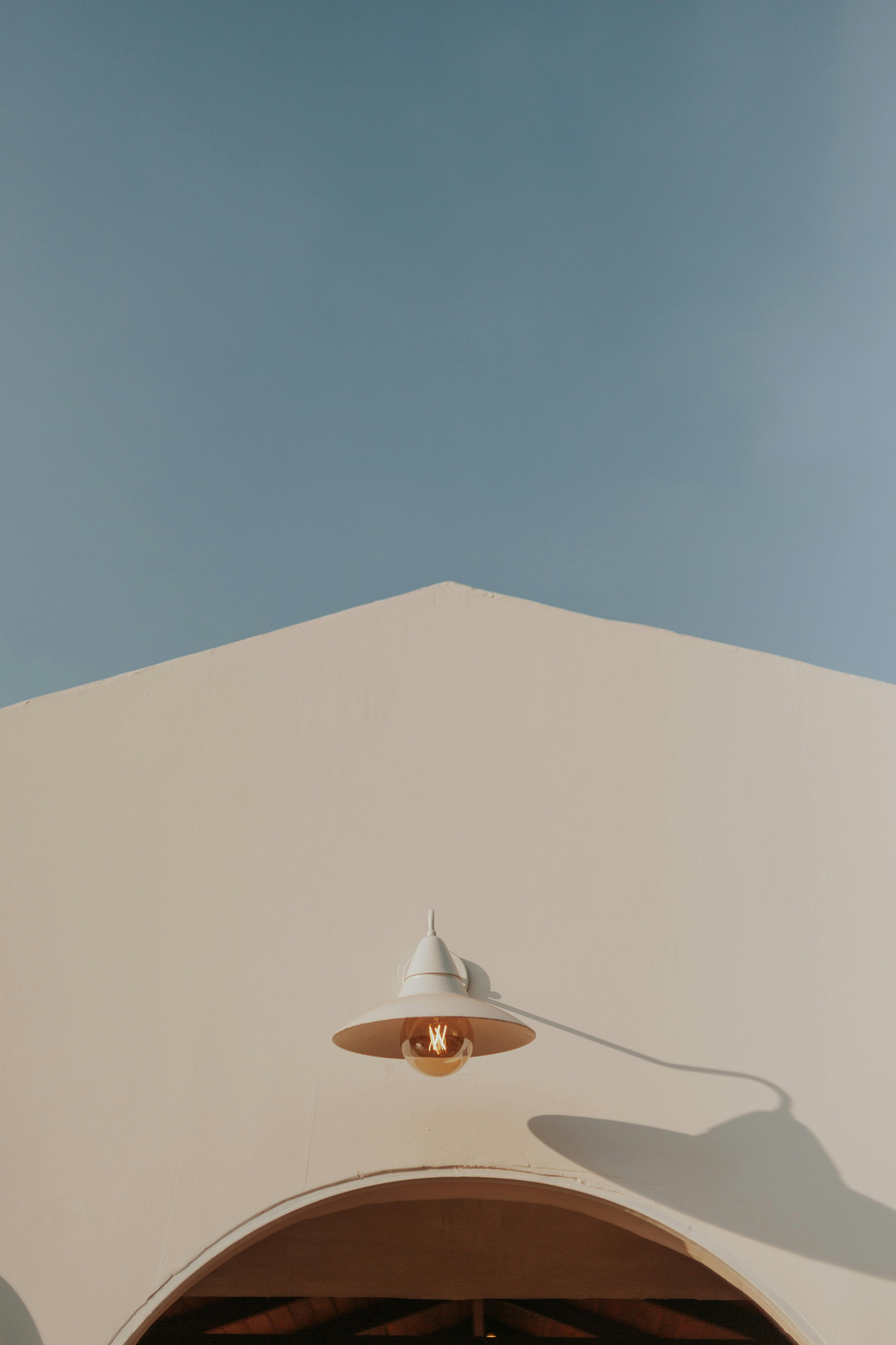 Gratis En moderne minimalistisk bygning med en hvid facade, udendørslampe og klar blå himmel. Lagerfoto