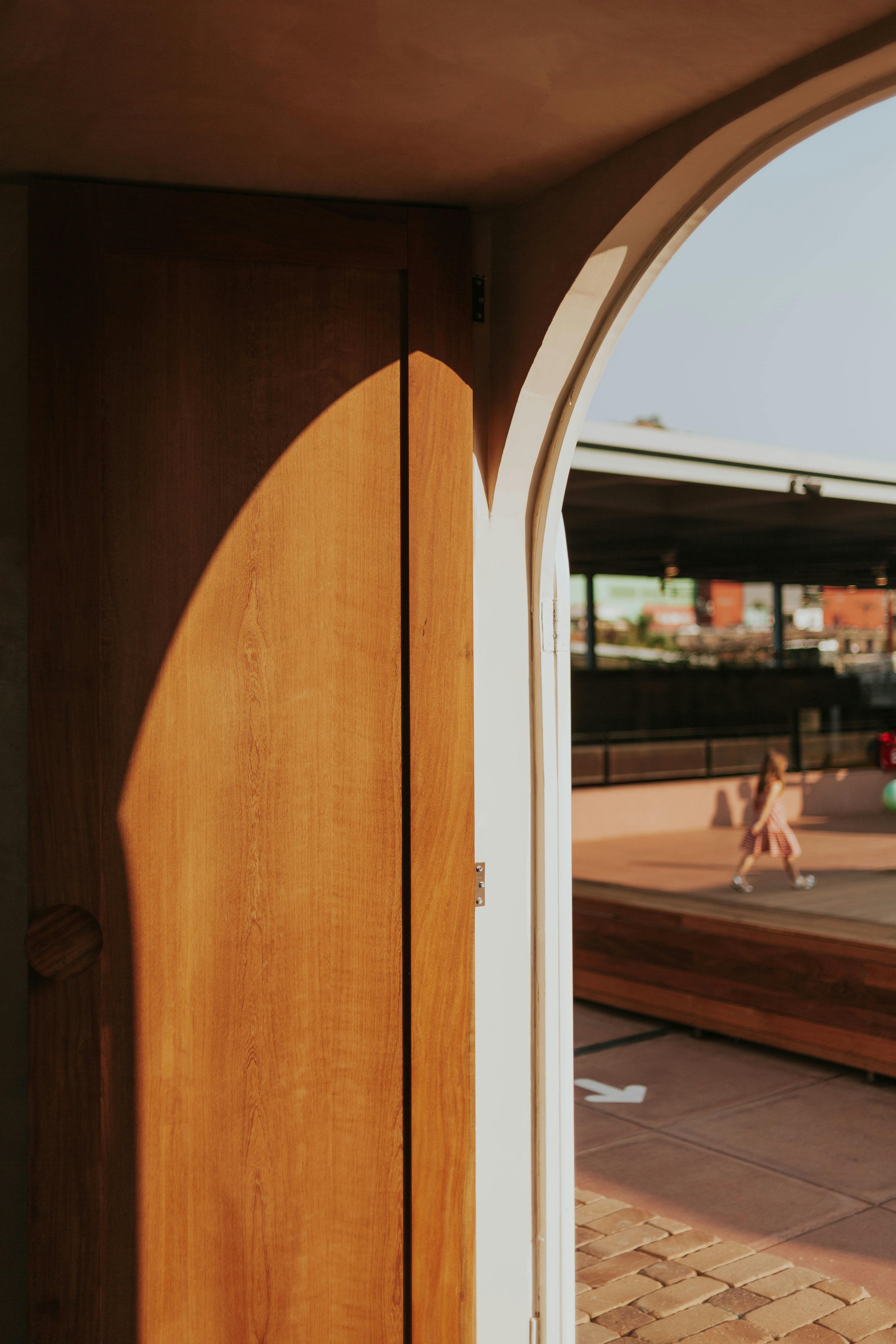 Gratis Varmt sollys kaster skygger på en tredøråpning med utsikt over en lekeplass utendørs. Arkivbilde