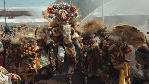 Colorful Mexican festival with traditional dancers in vibrant costumes and masks outdoors.