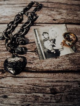 A nostalgic display of a wedding photo, rings, and a necklace on rustic wood.