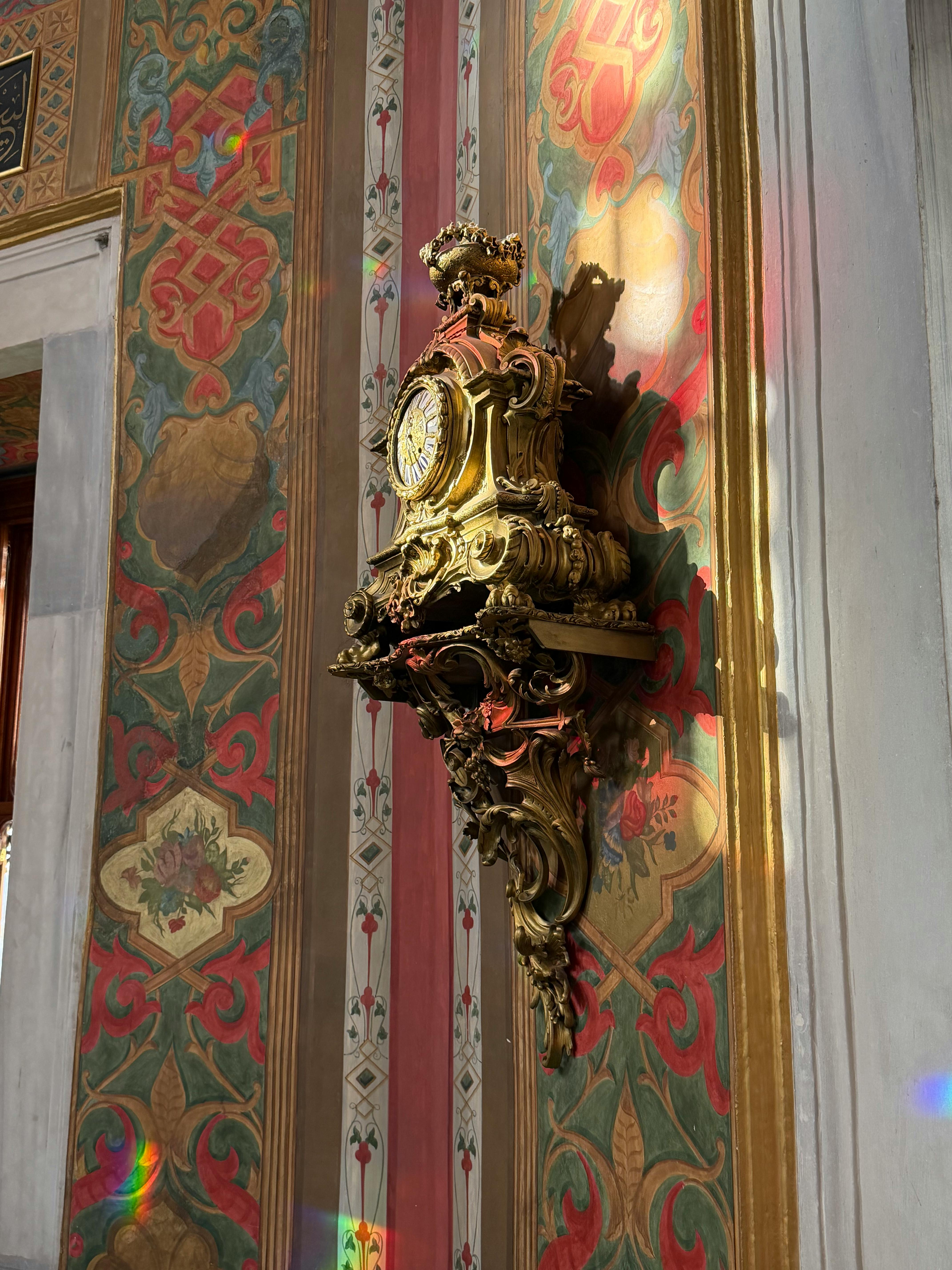 Gratis Uno splendido orologio antico su una parete riccamente decorata che riflette la luce vibrante del sole. Foto a disposizione