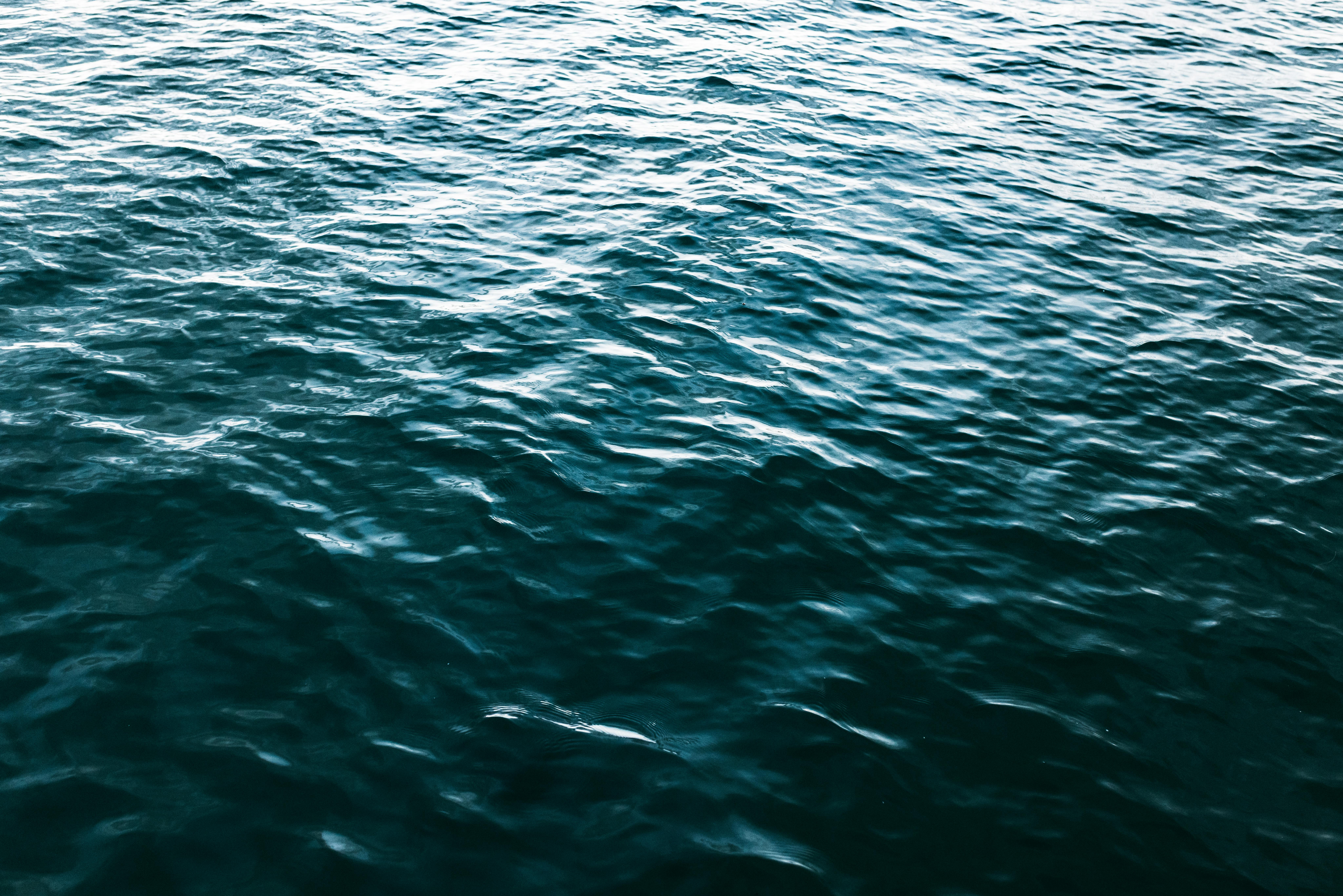 Ücretsiz Gün ışığı altında okyanus suyunun canlı dokularını ve zengin mavi tonlarını gösteren dinamik bir fotoğraf. Stok Fotoğraflar