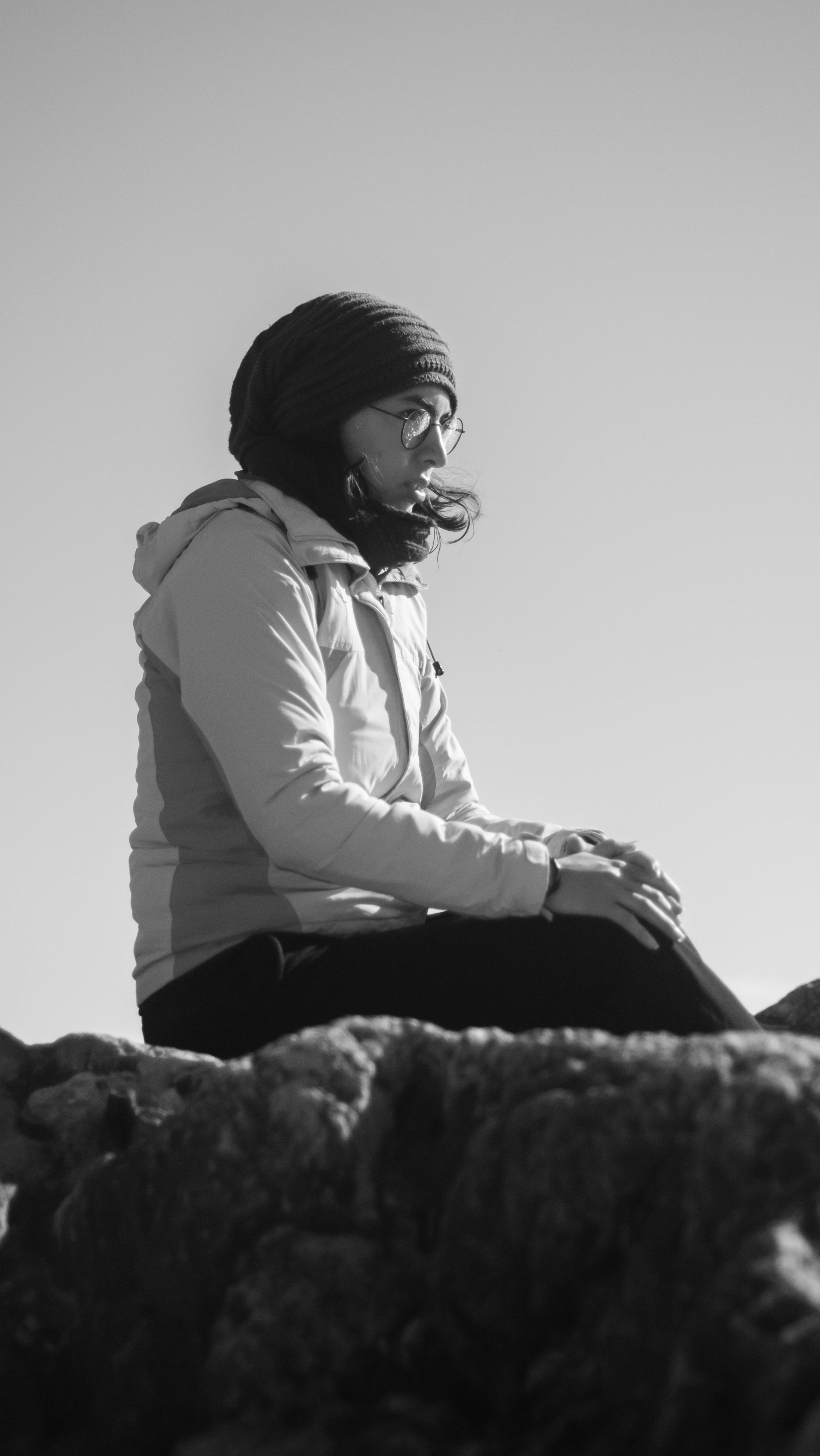 Gratuit O femeie cu un batic pe cap stă afară, gânditoare și senină, pe stânci. Fotografie de stoc