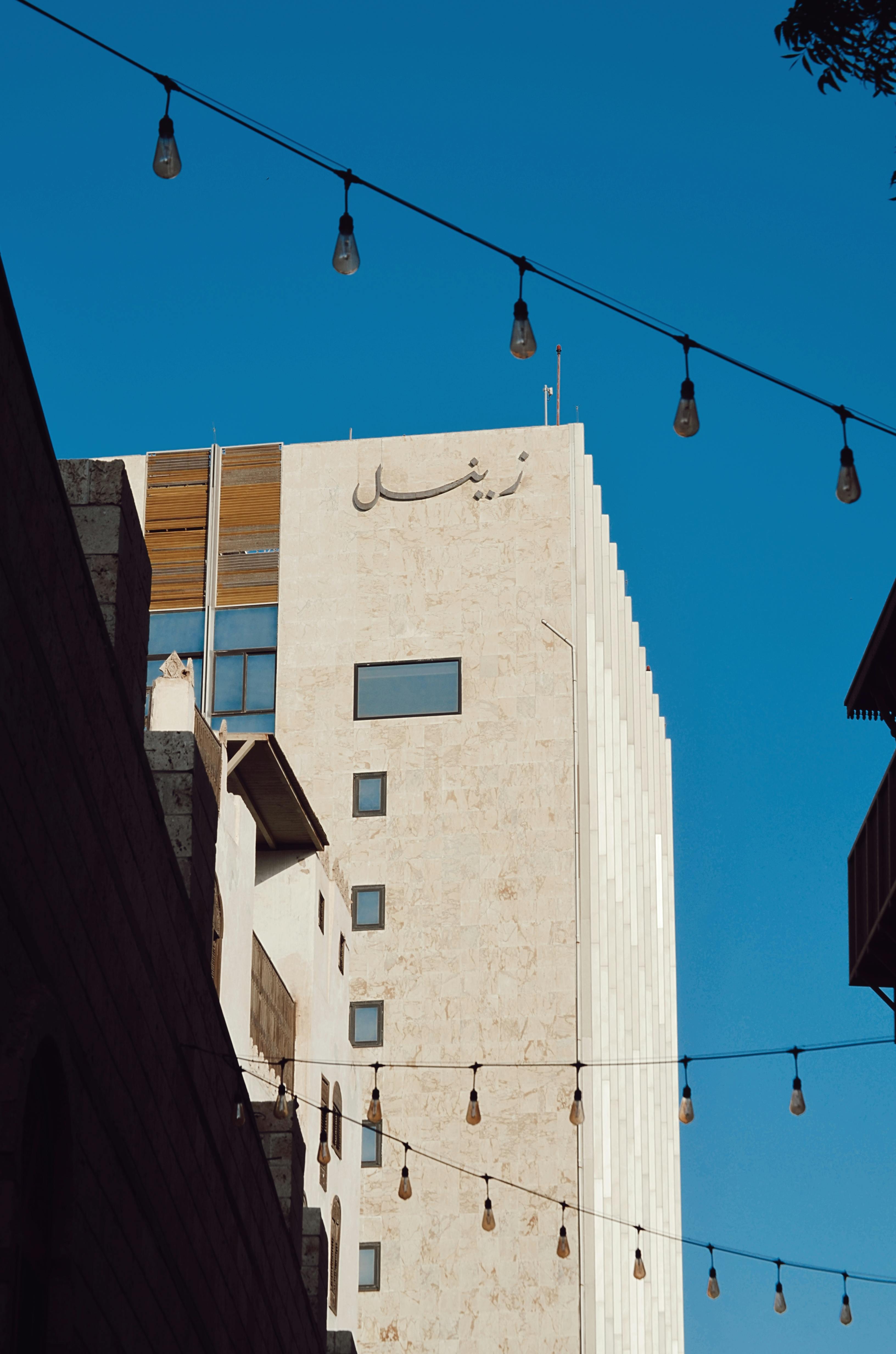 Bezpłatne Nowoczesny budynek w Dżuddzie w Arabii Saudyjskiej, otoczony wiszącymi lampkami pod czystym, błękitnym niebem. Zdjęcie z galerii