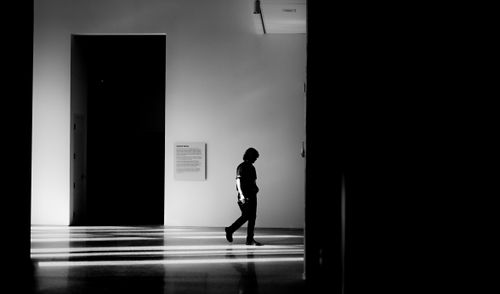 Free Black and white photo of a person silhouetted walking in a modern, minimalist indoor space. Stock Photo