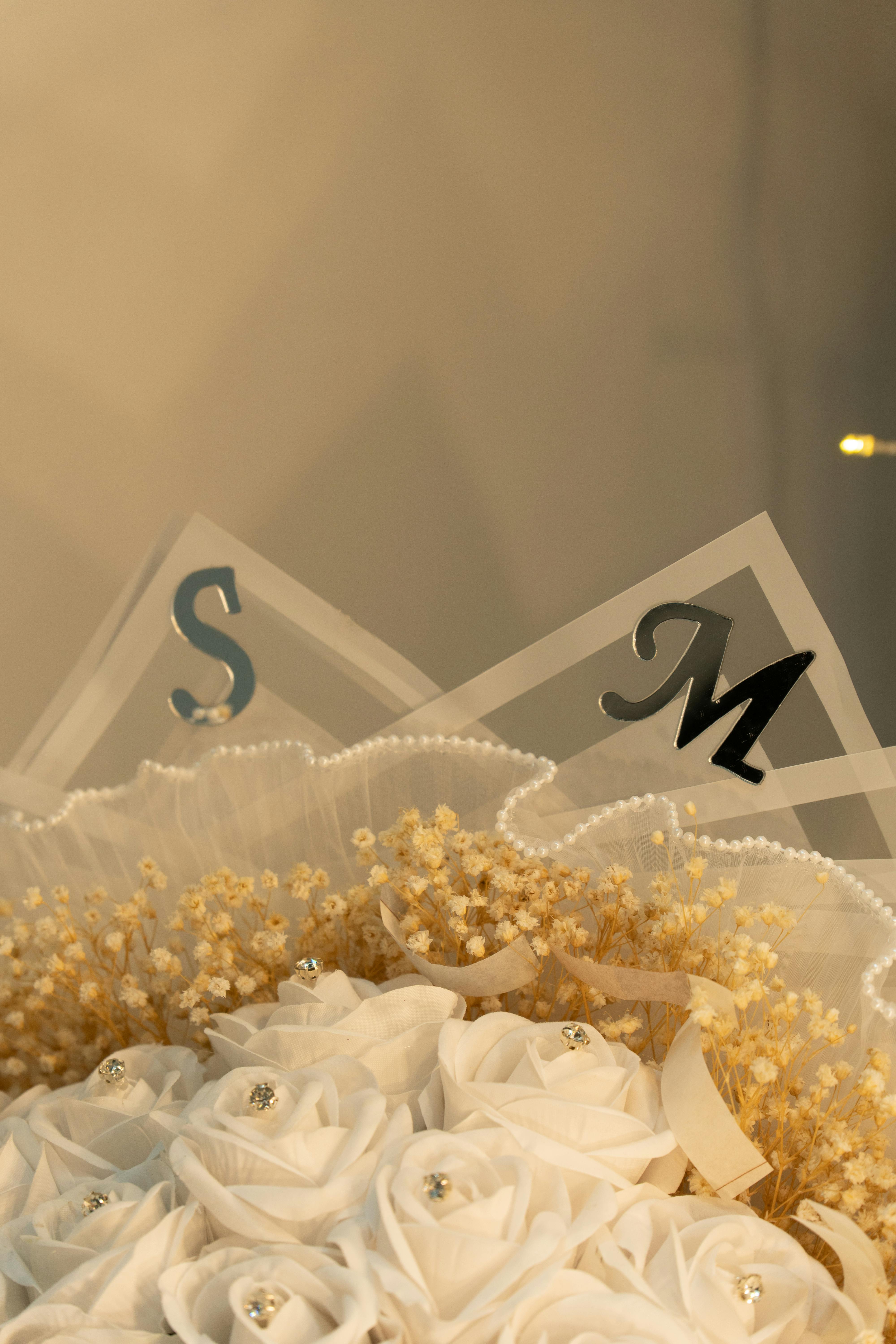 Free Close-up of an elegant wedding bouquet featuring white roses and decorative letters. Stock Photo