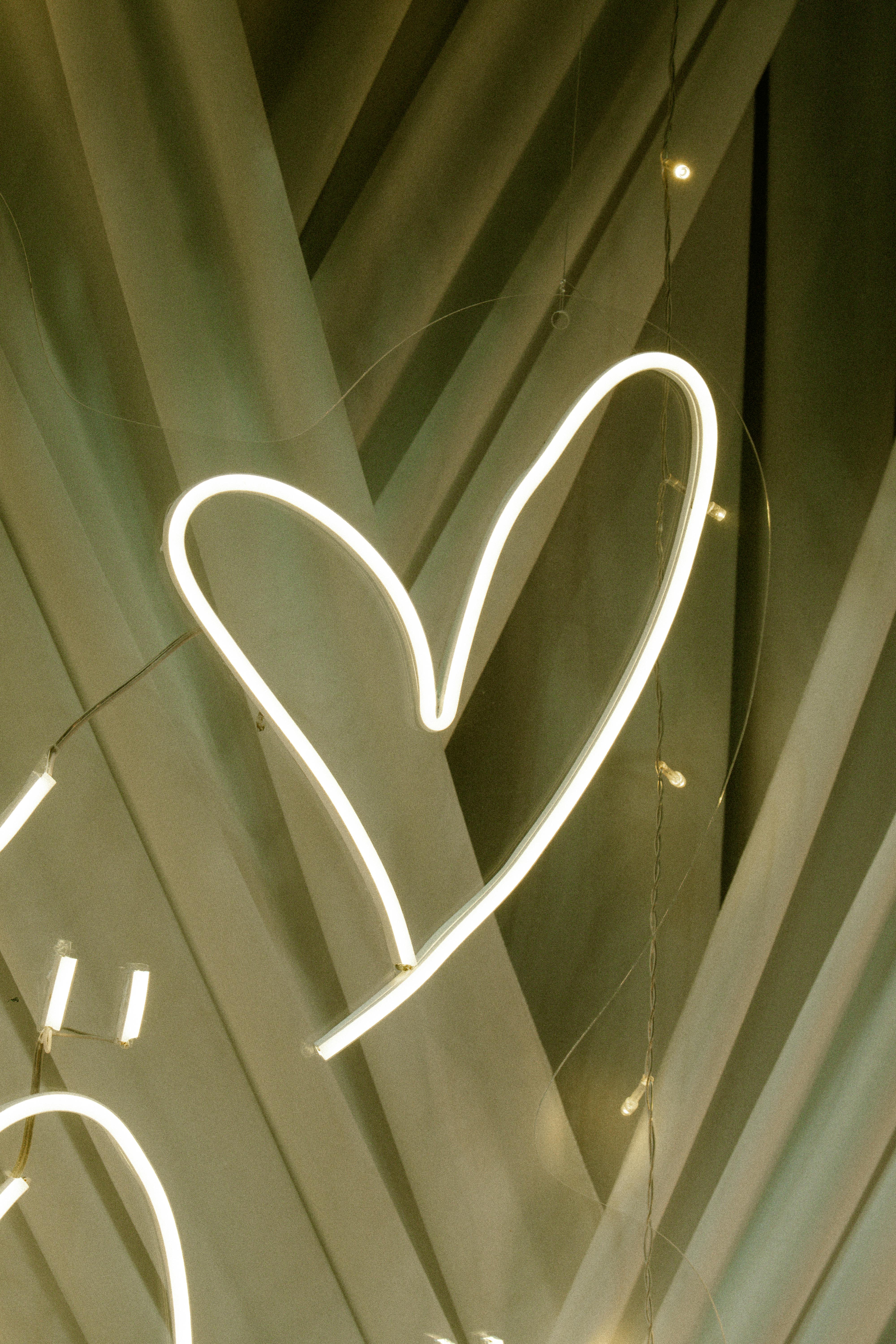 Gratis Moderna opera d'arte astratta raffigurante un cuore luminoso al neon su uno sfondo geometrico, immortalato di notte. Foto a disposizione