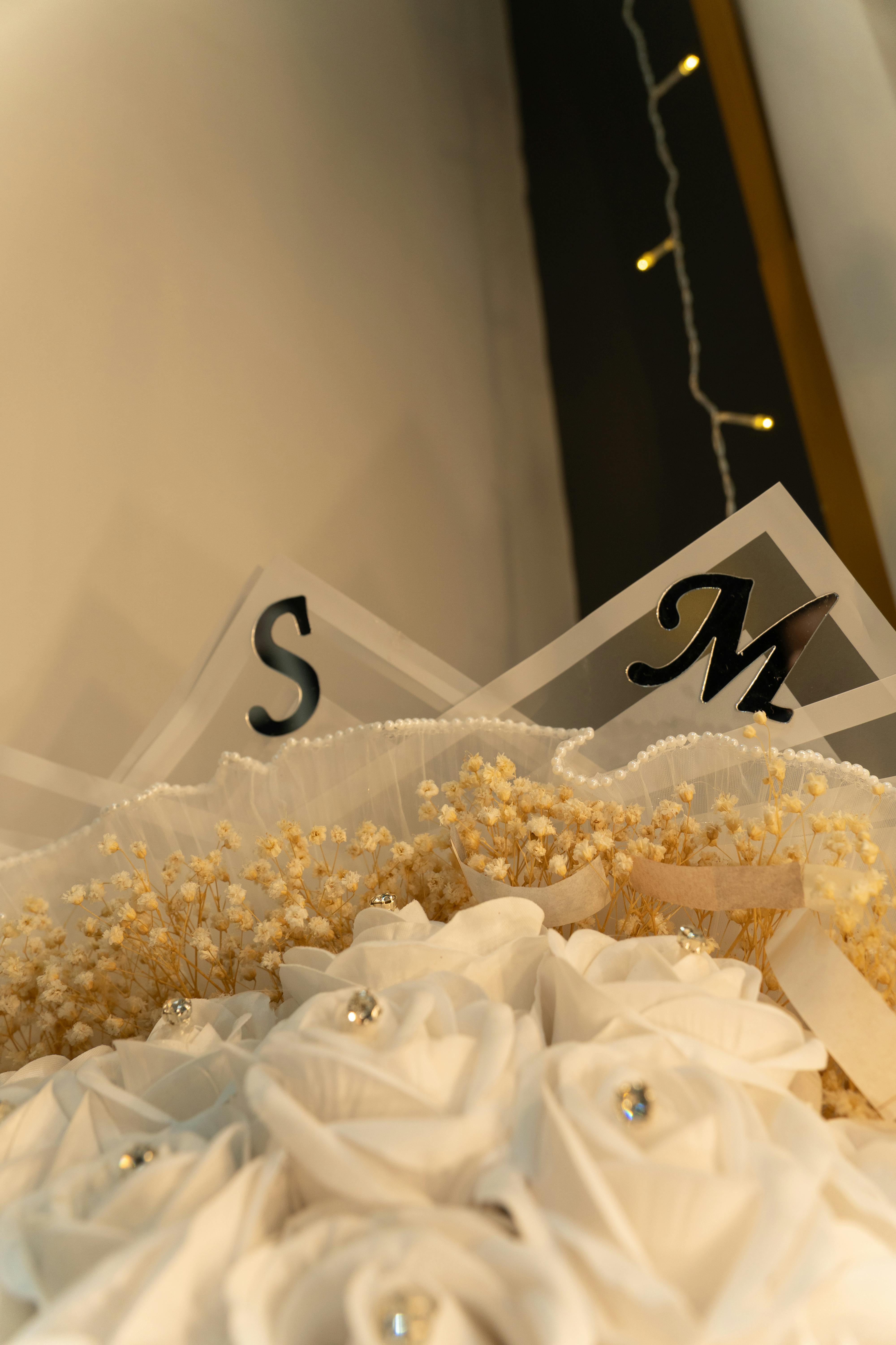 Gratuit Motif floral artistique avec des roses blanches et des lettres décoratives sur un fond chaleureux et lumineux. Photos