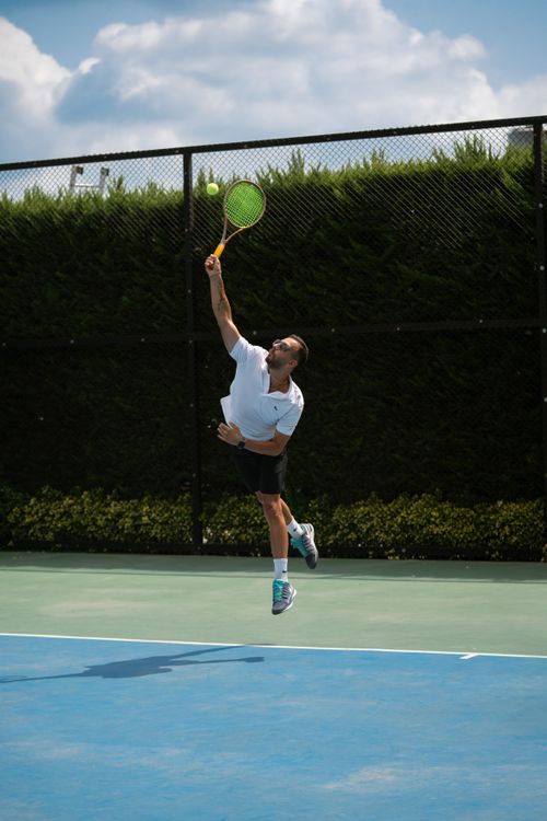 Free Athlete performs a powerful tennis serve on an outdoor court in Iran. Stock Photo