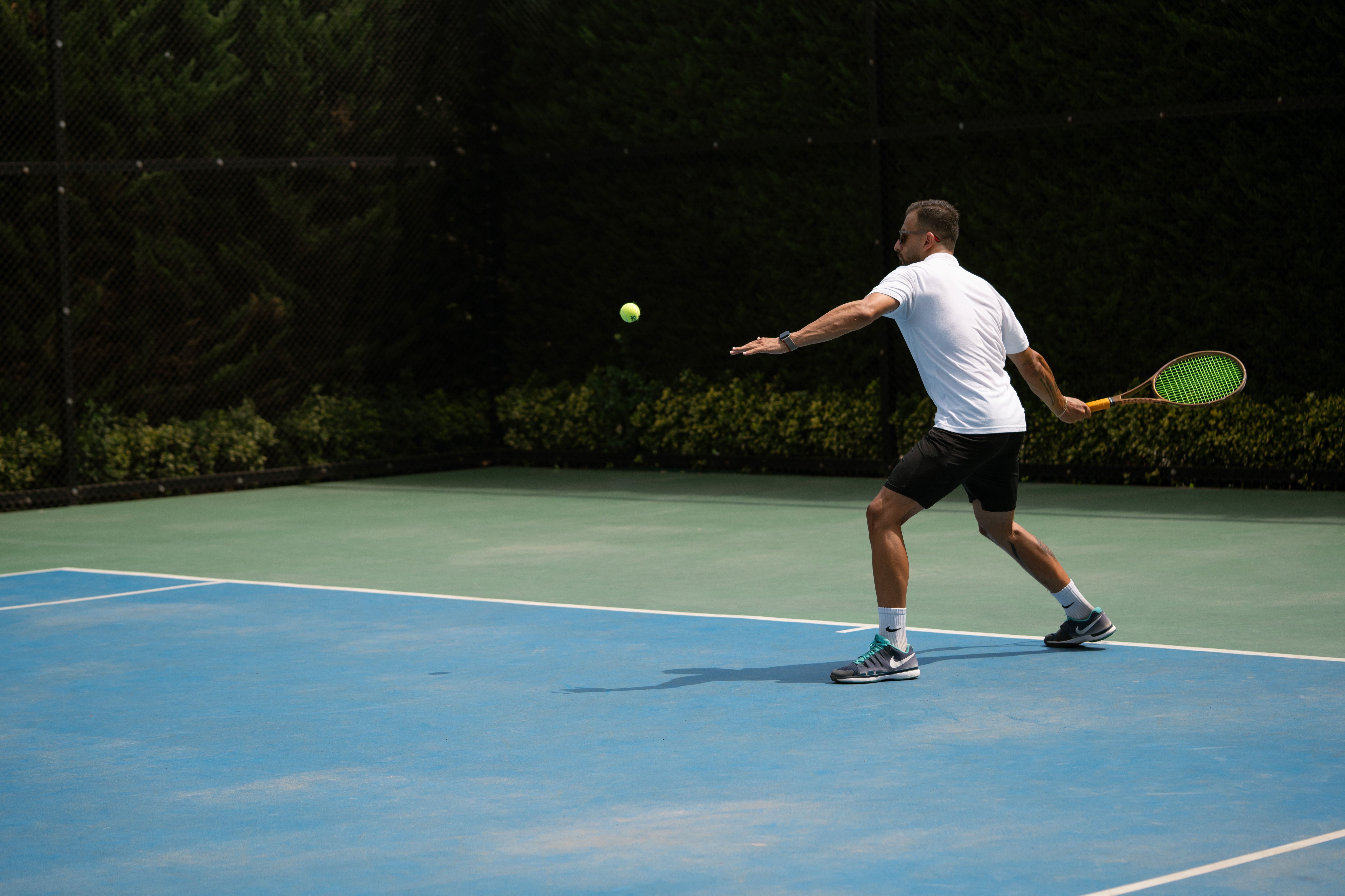 Tennis photo featuring Tennis player hitting a backhand shot on a sunny outdoor court in Iran.