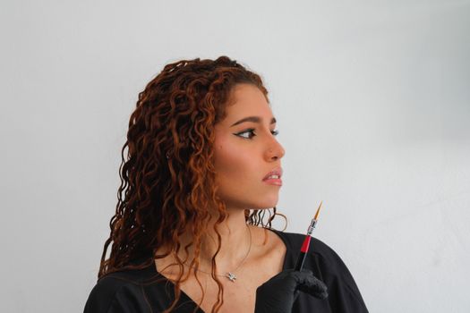 Artistic young woman holding a brush, expressing creativity and focus.