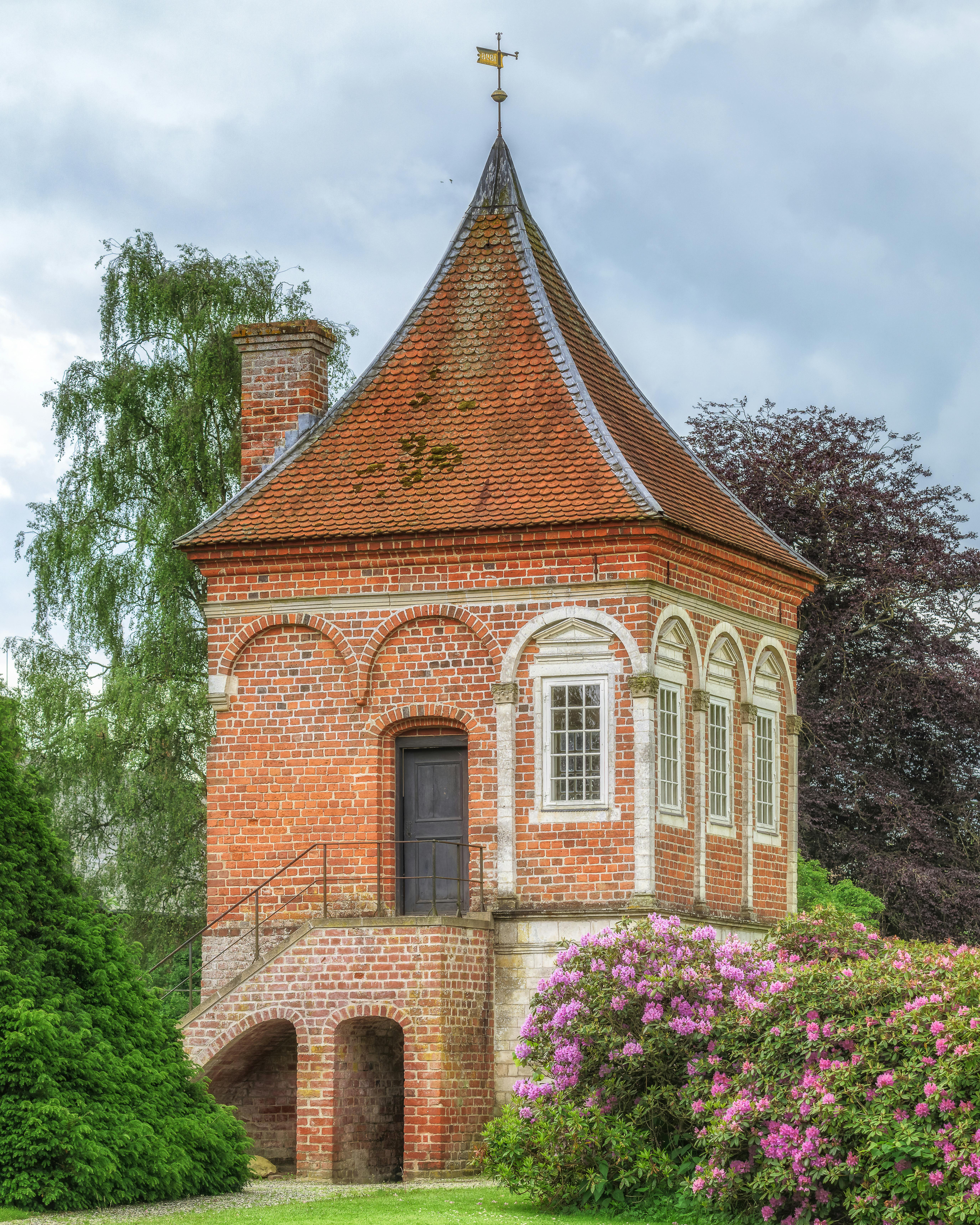 Gratuit Pavilion pitoresc din cărămidă, înconjurat de verdeață vibrantă și flori, care prezintă arhitectură clasică. Fotografie de stoc