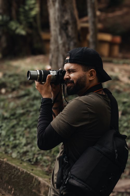 Free Photographer taking pictures in a lush forest setting, focused and equipped. Stock Photo