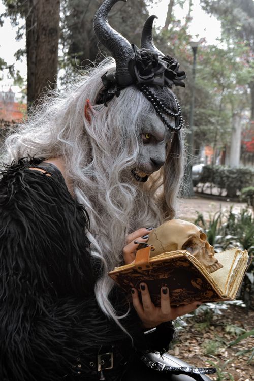 Free Person in a fantasy costume holding a skull and ancient book in a park setting. Stock Photo