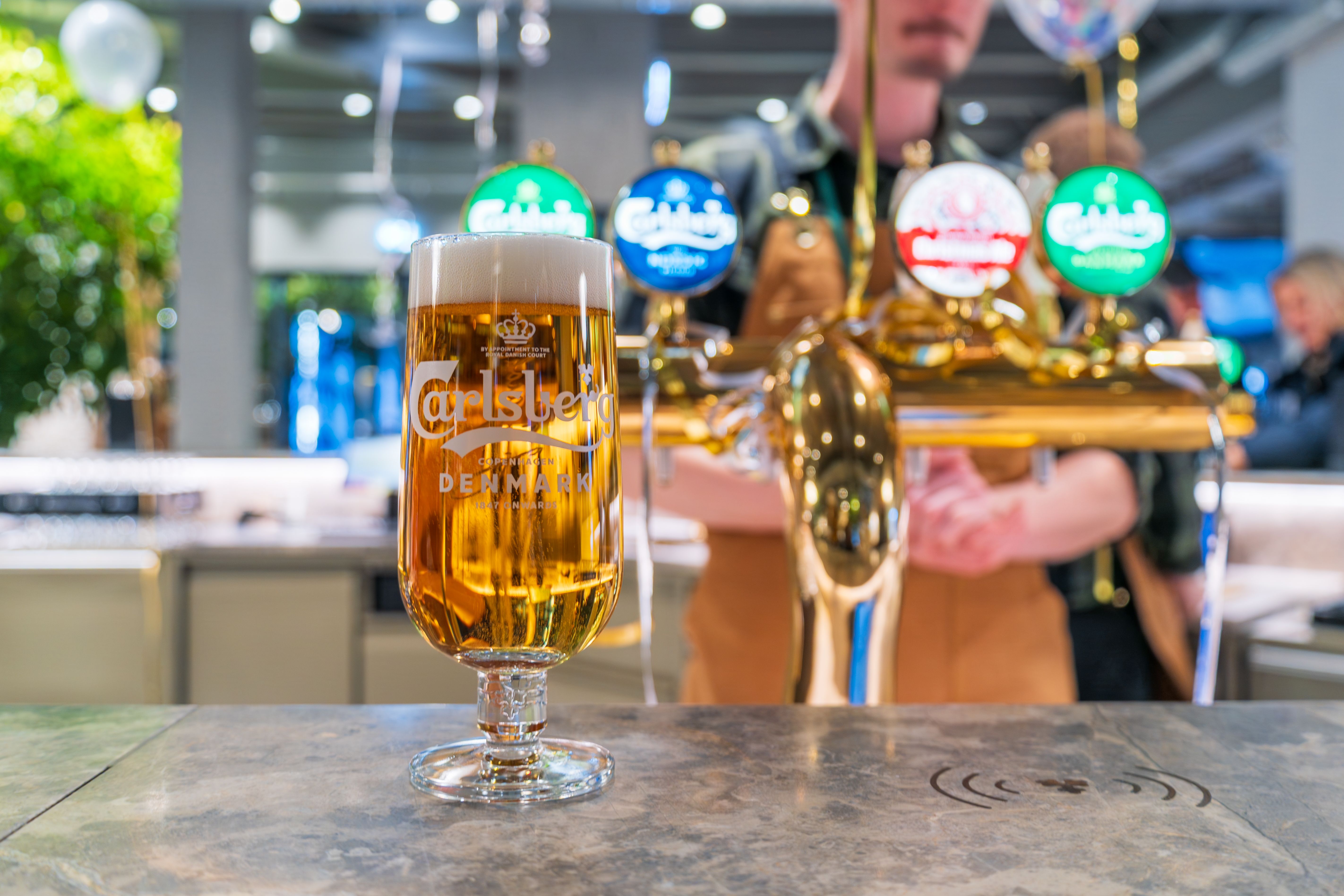 A Carlsberg beer glass at the brewery bar in Copenhagen, Denmark, showcasing vibrant beer culture.