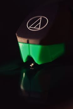 A detailed shot of a turntable stylus, highlighting its delicate needle on a vinyl record.