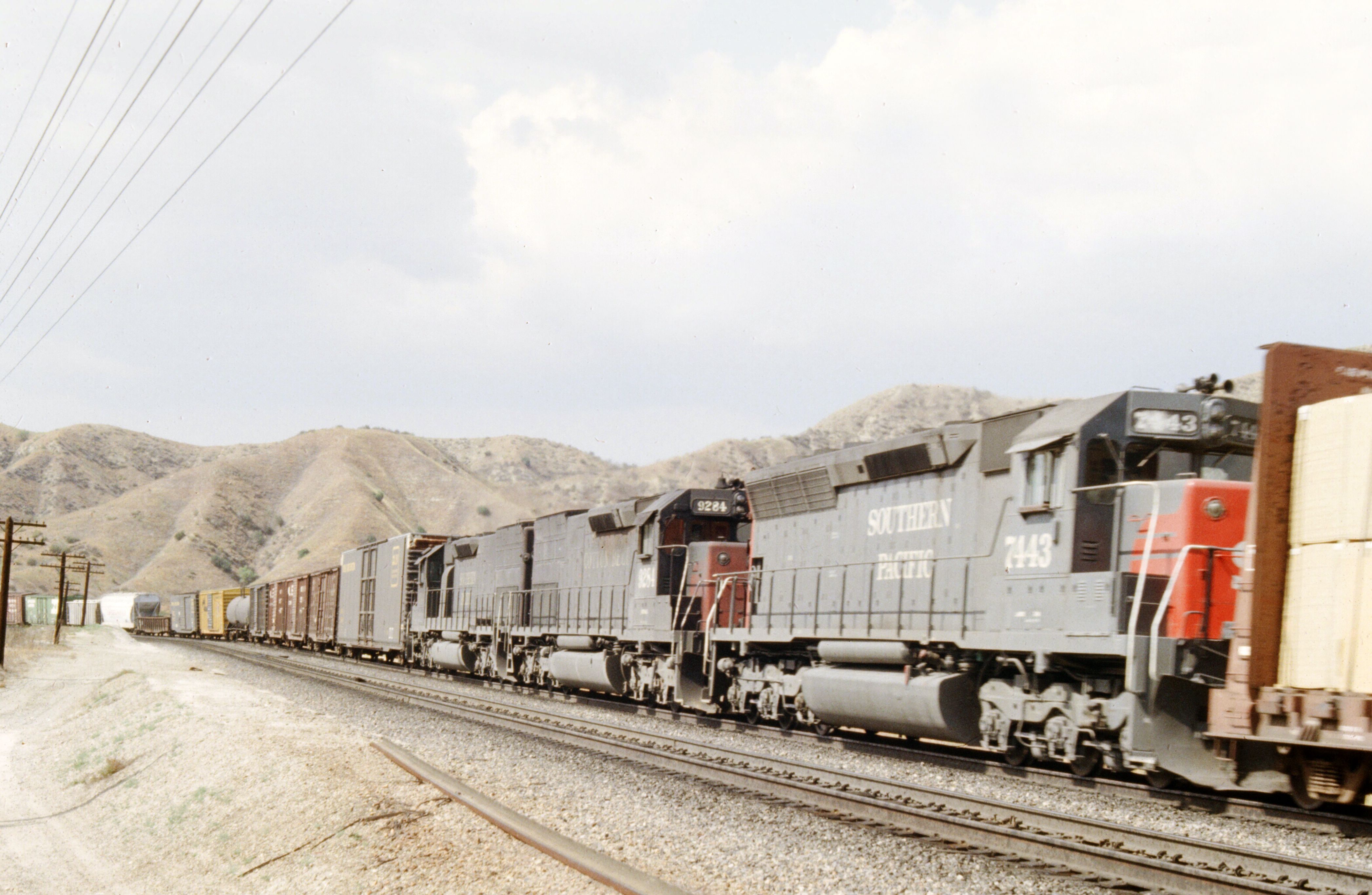 A freight train moving through a scenic mountainous region, showcasing industrial transportation.