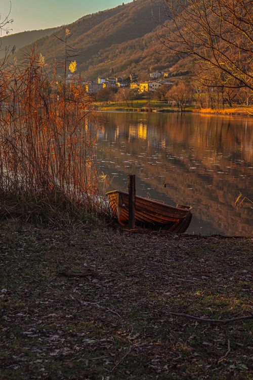 Tranquil lake scene at sunset with wooden boat · Free Stock Photo
