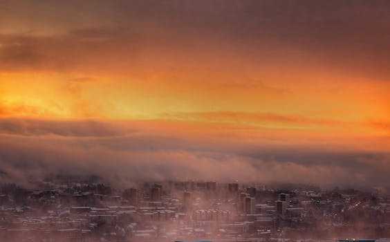 Dramatic aerial view of Oslo skyline enveloped in fog at golden sunset.
