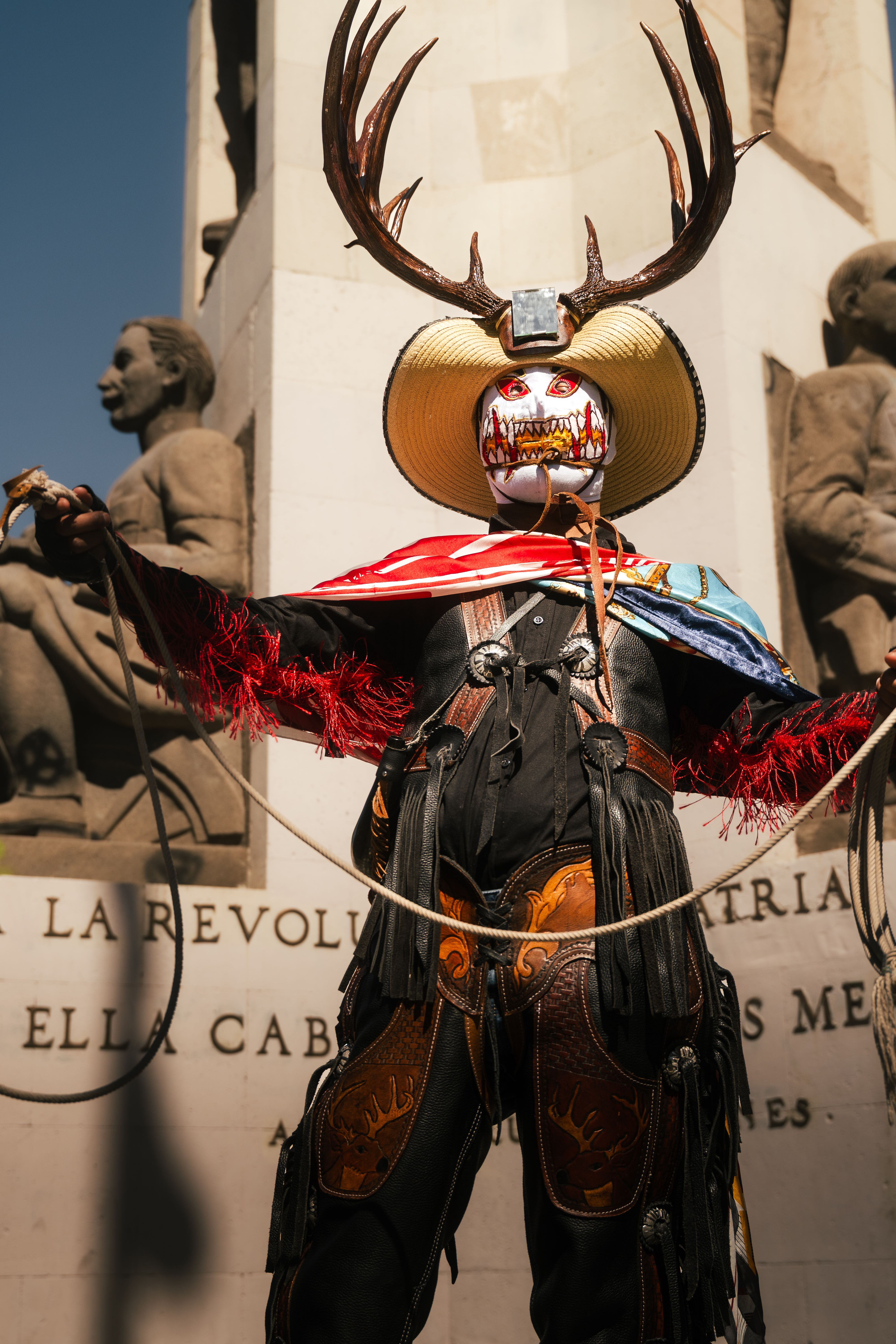 Person in traditional costume with antlers at a monument in Pachuca, Mexico.