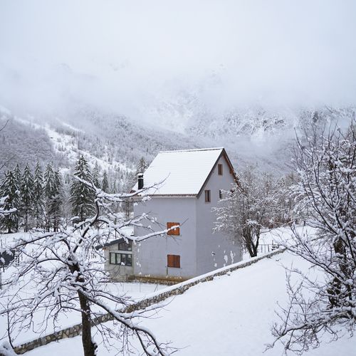 Free Charming winter scene with a snow-covered house in Valbonë, Albania, surrounded by mountains. Stock Photo
