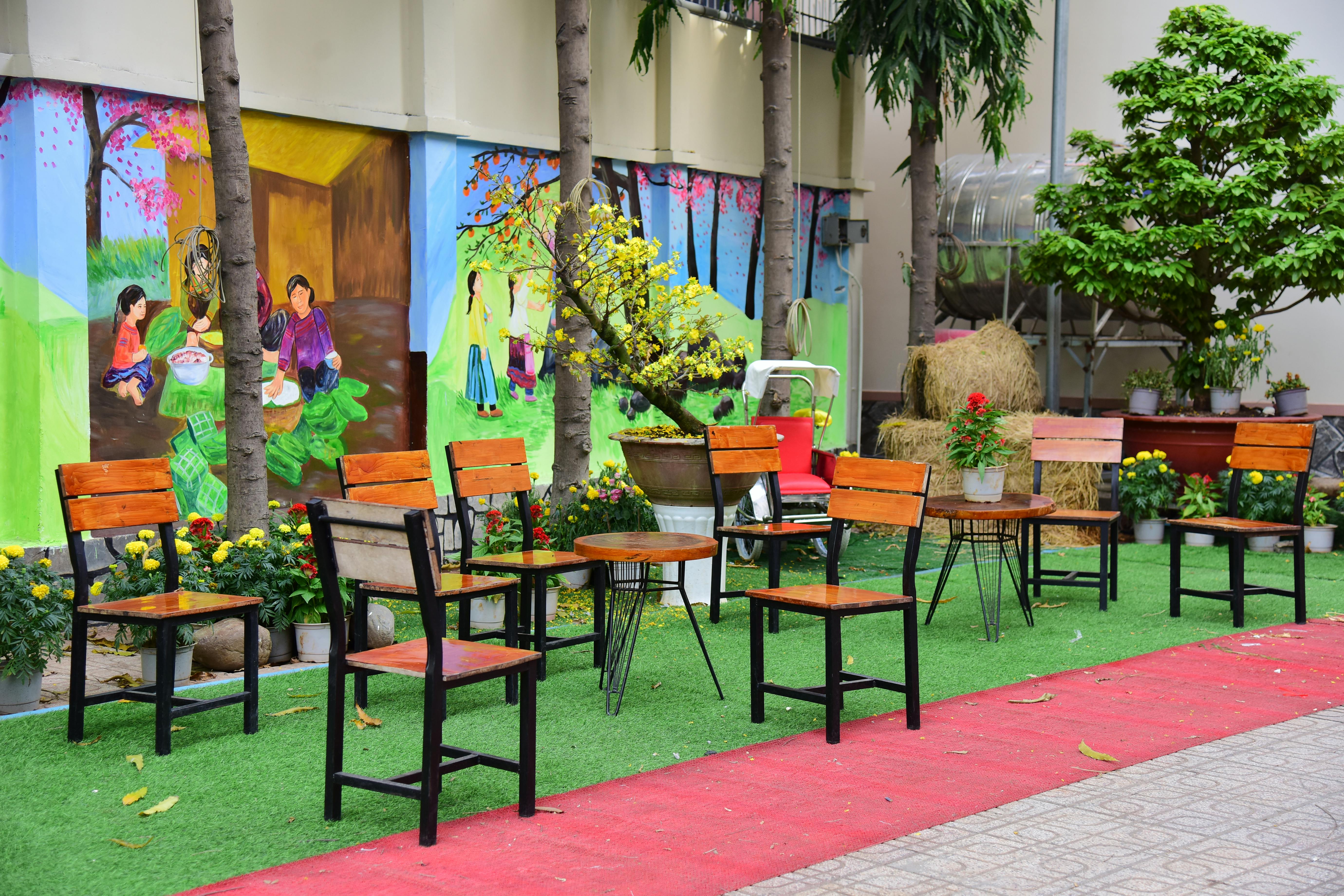 Gratis Area tempat duduk luar ruangan yang semarak dengan mural warna-warni dan tanaman hijau yang rimbun, ideal untuk tema artistik dan budaya. Foto Stok