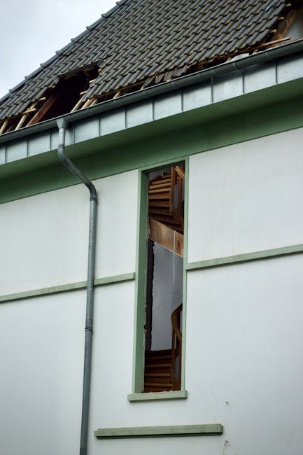 Photo by Peter Dyllong An exterior view of a damaged house showing a broken roof and exposed interior structure.