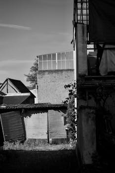 Black and white urban alley scene with vintage buildings and shadows.