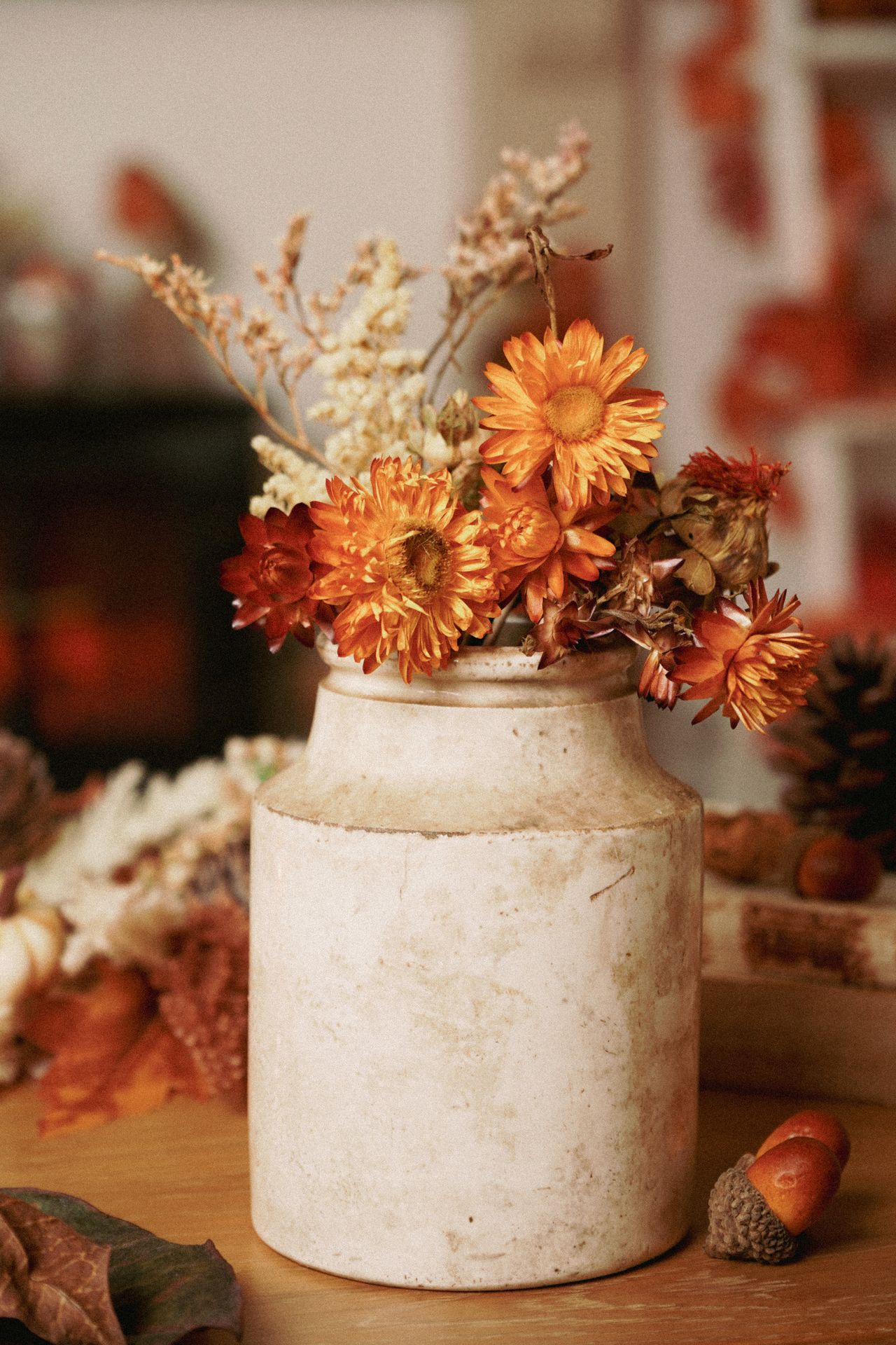 Dried orange strawflowers in a vintage white stoneware crock vase