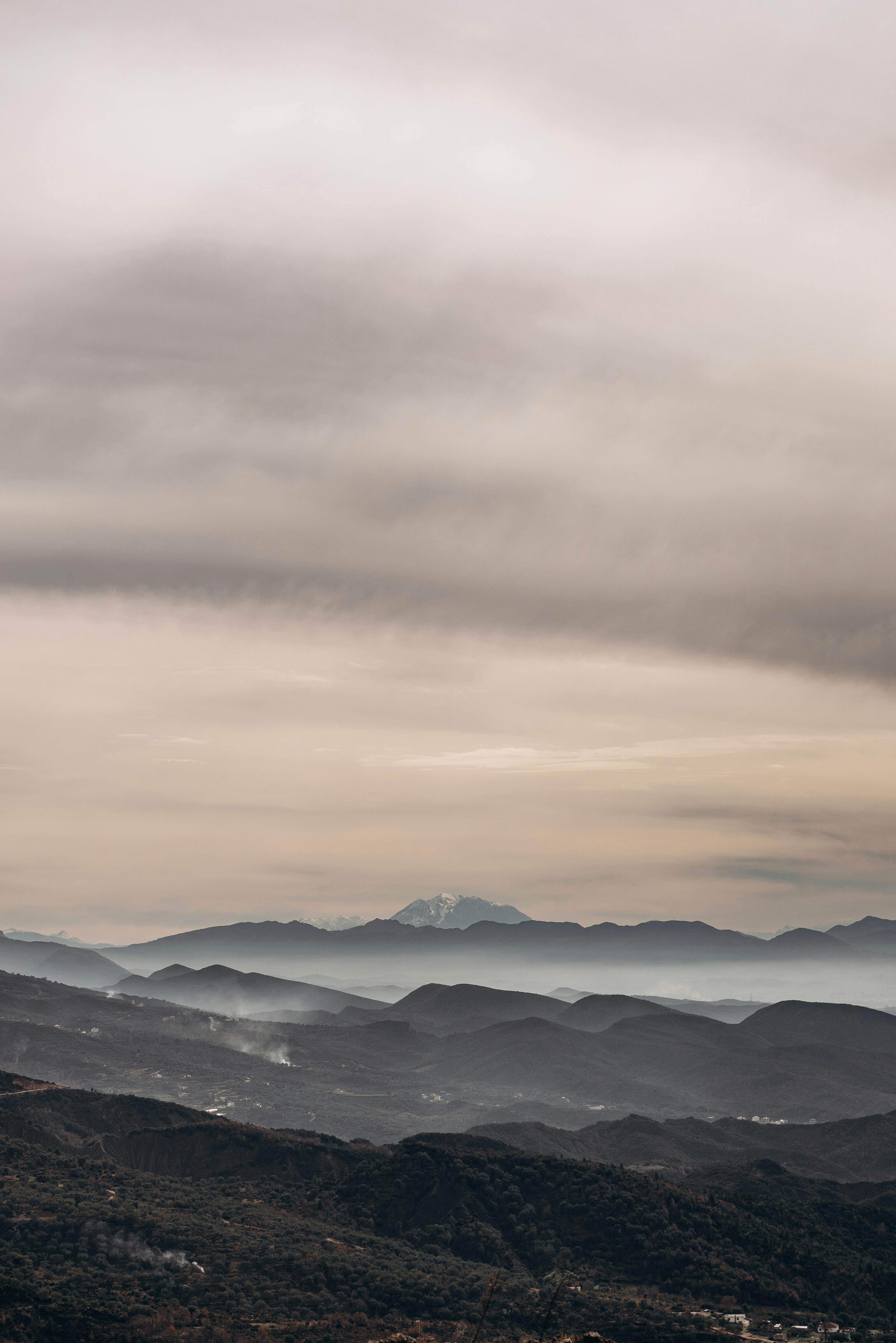Bezpłatne Spokojny widok pasma górskiego z zachmurzonym niebem, ukazujący naturalne piękno. Zdjęcie z galerii