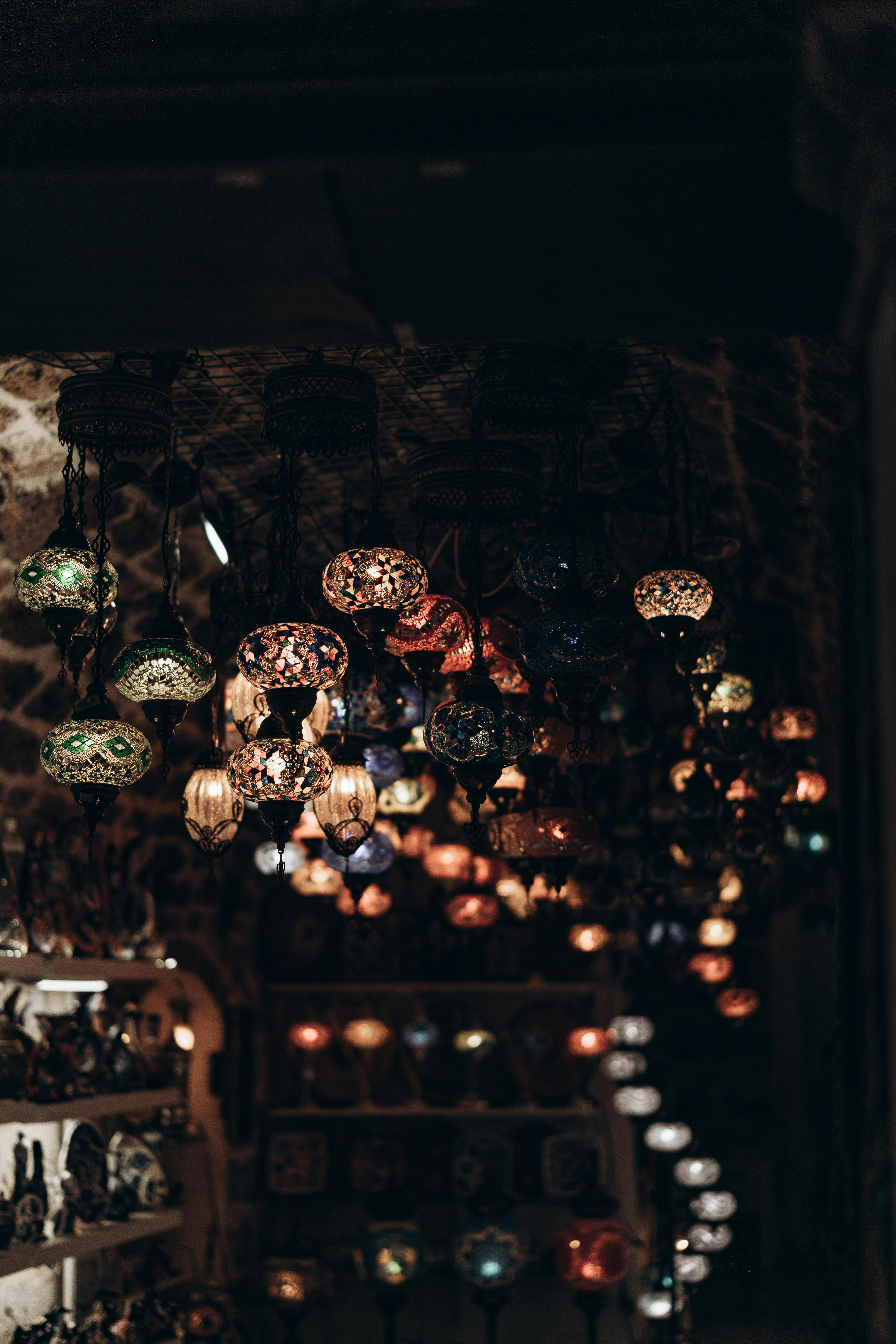 Gratis Una exhibición de vibrantes lámparas de mosaico turcas colgadas en un bazar poco iluminado, creando una atmósfera cálida y exótica. Foto de stock