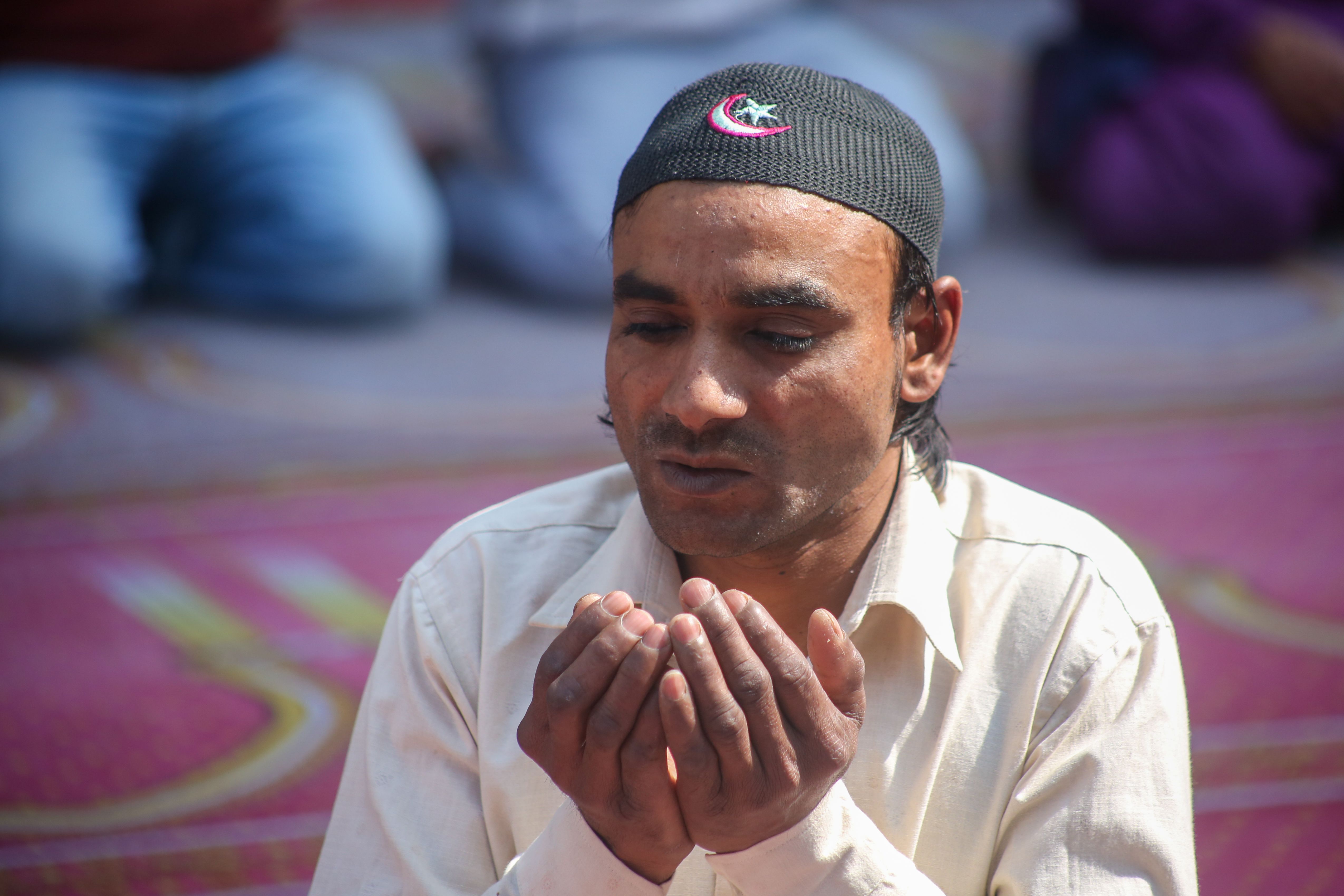 Man Praying Outdoors in Traditional Cap · Free Stock Photo