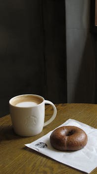 Warm latte and bagel on a wooden table, perfect for a cozy indoor coffee break.