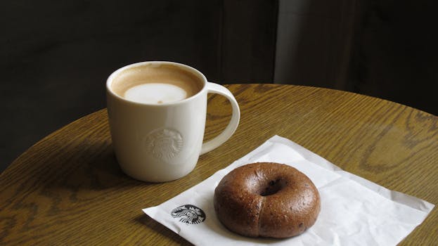 Enjoy a relaxing coffee break with a warm latte and a chocolate bagel in a cozy cafe setting.