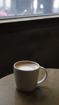 Warm cup of coffee on a wooden table by the window in a cozy cafe setting.