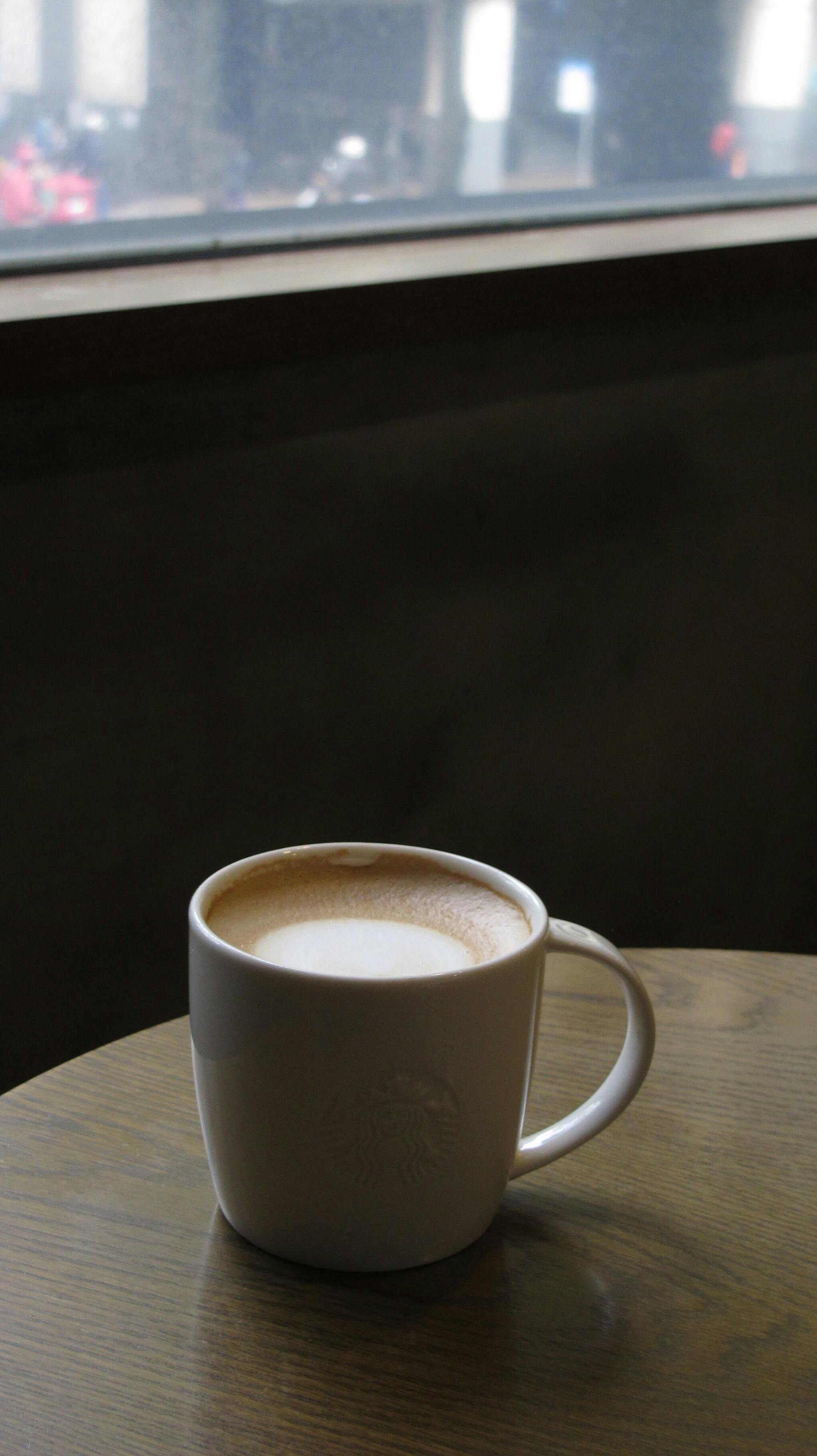 Gratis Varm kopp kaffe på et trebord ved vinduet i en koselig kafésetting. Arkivbilde