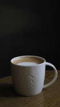 Dark and moody shot of a Starbucks coffee mug on a wooden table, perfect for beverage-focused content.