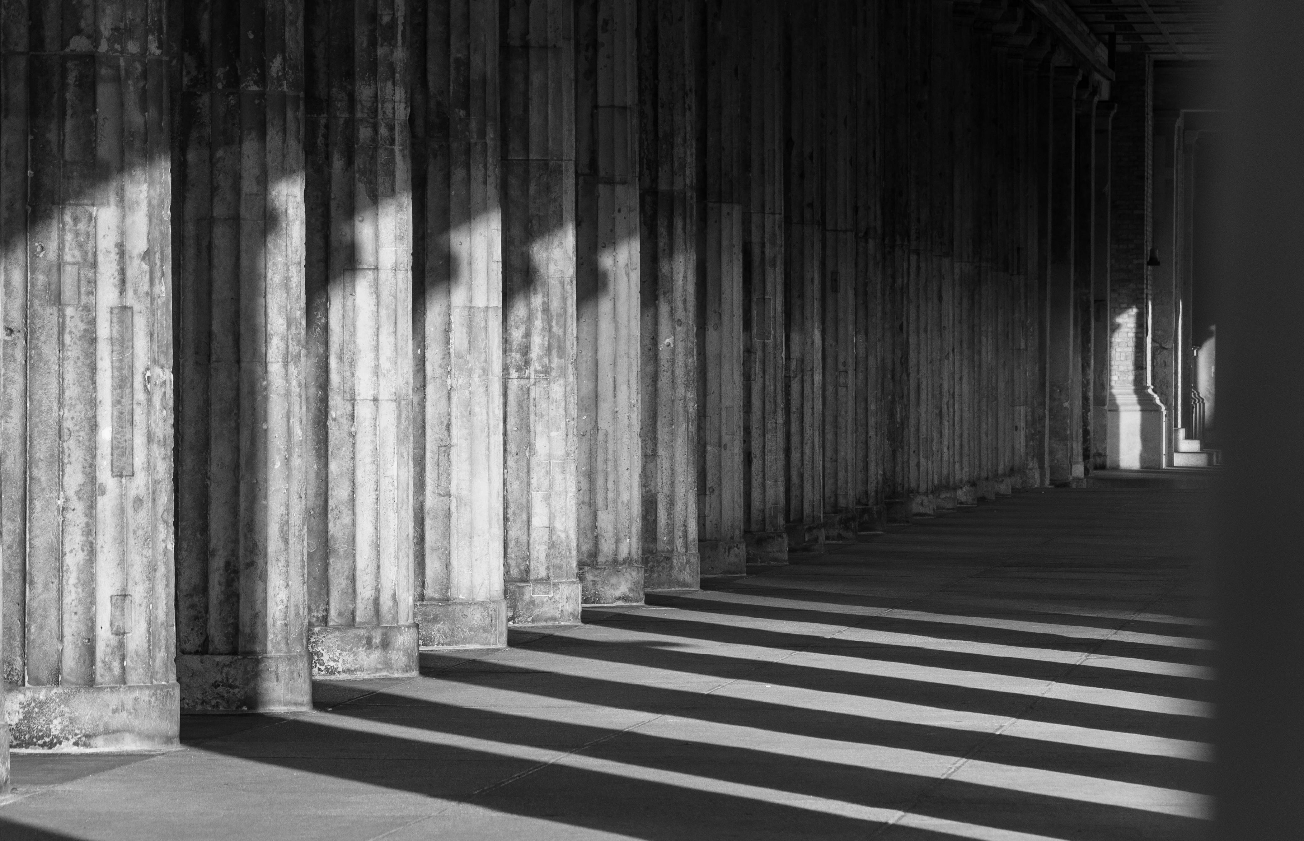 Δωρεάν Ασπρόμαυρη φωτογραφία αρχιτεκτονικών κιόνων που ρίχνουν δραματικές σκιές. Φωτογραφία από στοκ φωτογραφιών
