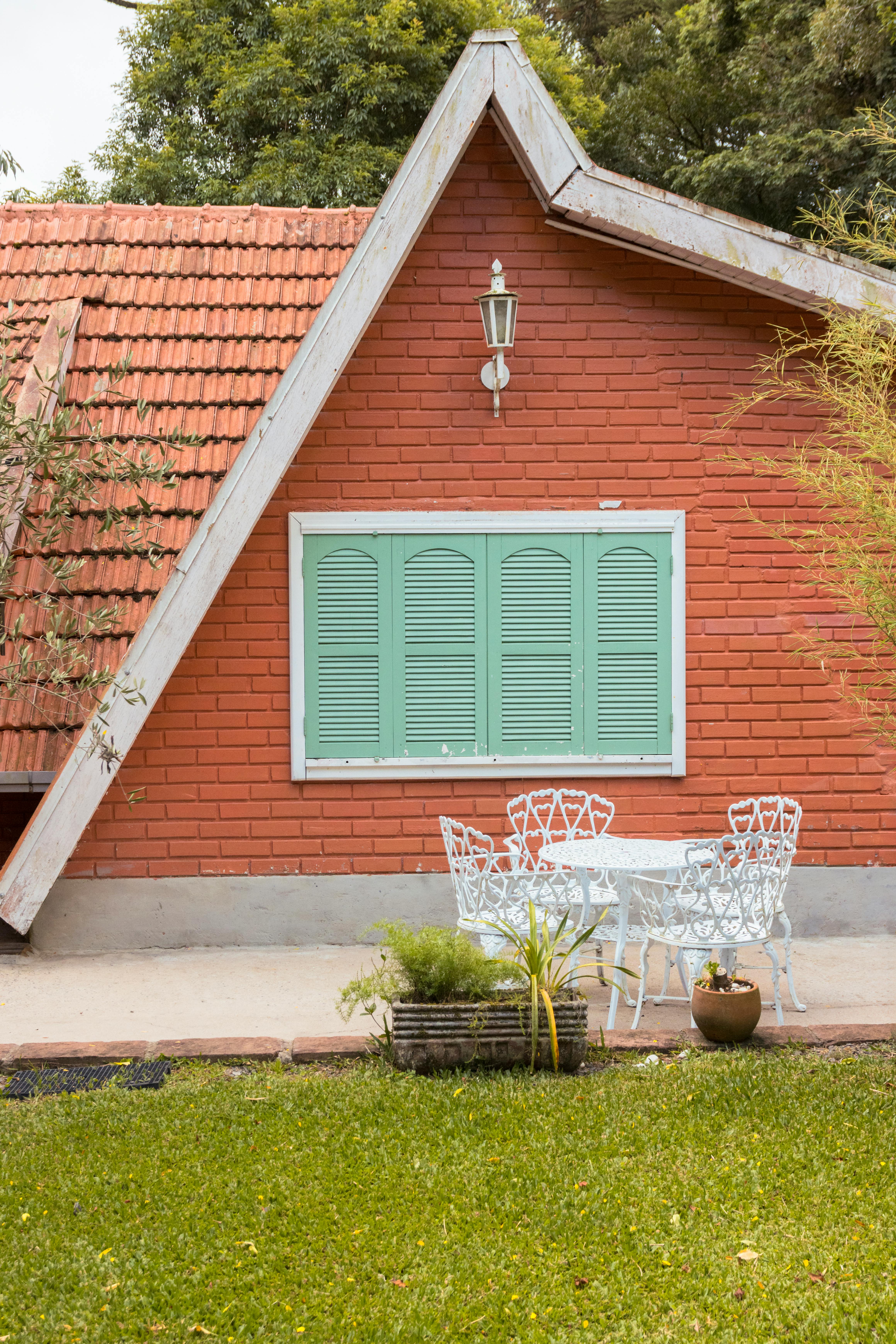 Gratis En hyggelig rød murstenschalée med grønne skodder og udendørs siddepladser i Gramado, Brasilien. Lagerfoto