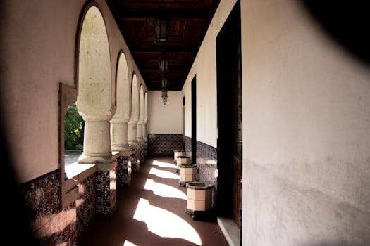 Beautiful arched corridor with natural light casting shadows, elegant architecture and rustic decor.