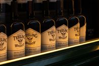 Row of Teeling Irish whiskey bottles showcased with soft golden lighting, embodying luxury and quality.